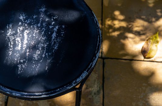 Sunlight shining into black steel chair in the backyard. Selective focus.