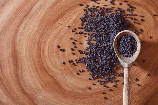 Black sesame with wooden spoon lies on a wooden slice. Close-up. Macro effect photo. With copy space. High quality photo