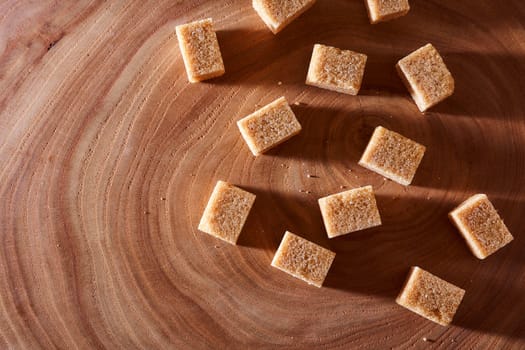 Brown cane sugar pieces on a slice, a plank of wood. High quality photo