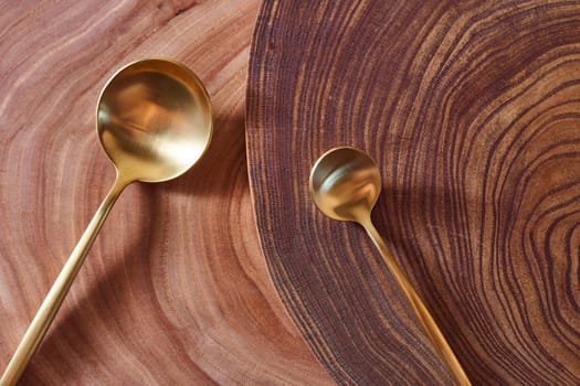 The golden spoon lies on a slice of a tree. wooden table. With copy space. High quality photo