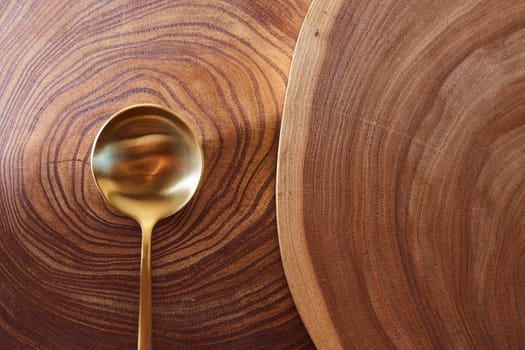 The golden spoon lies on a slice of a tree. wooden table. With copy space. High quality photo