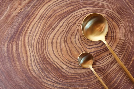 The golden spoons lies on a slice of a tree. wooden table. With copy space. High quality photo