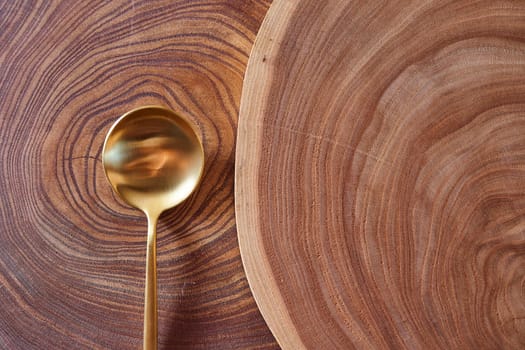 The golden spoon lies on a slice of a tree. wooden table. With copy space. High quality photo