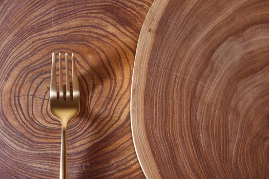 The golden fork lies on a slice of a tree. wooden table. High quality photo