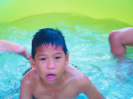 A boy playing in the pool and Smile happily.