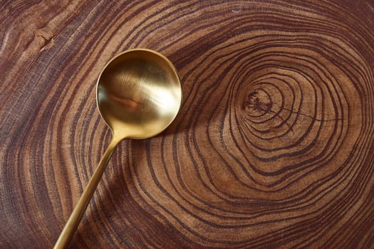 The golden spoon lies on a slice of a tree. wooden table. With copy space. High quality photo