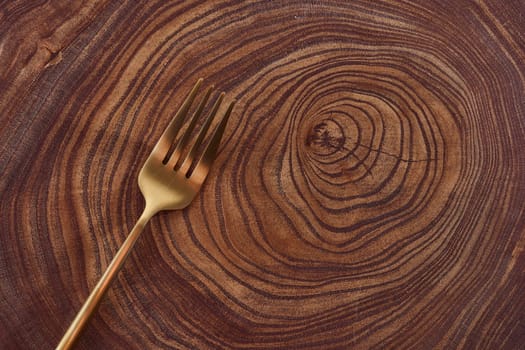 The golden fork lies on a slice of a tree. wooden table. High quality photo