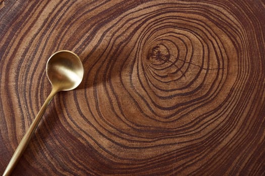 The golden spoon lies on a slice of a tree. wooden table. With copy space. High quality photo