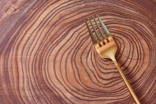 The golden fork lies on a slice of a tree. wooden table. High quality photo