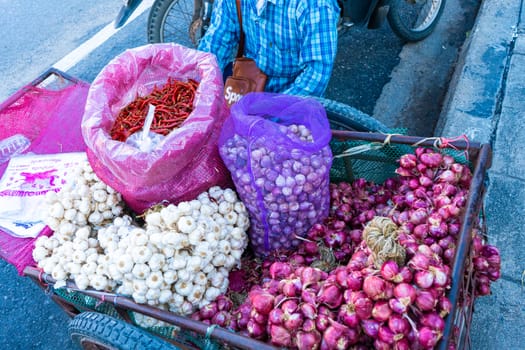 Asian street vendor sells seasonings, onions, garlic and peppers on a cart on the street