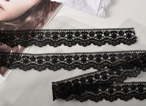 Tapes of black gentle guipure, beauty lace fabric on light background. Elastic material. Using for Atelier and needlework store.