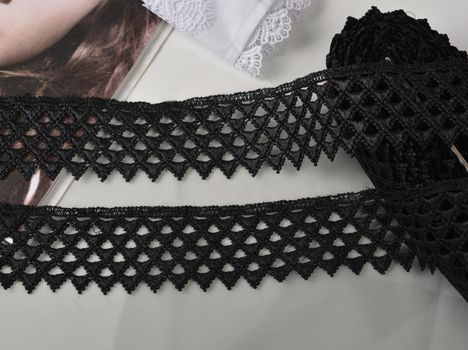 Tapes of black gentle guipure, beauty lace fabric on light background. Elastic material. Using for Atelier and needlework store.