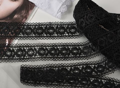 Tapes of black gentle guipure, beauty lace fabric on light background. Elastic material. Using for Atelier and needlework store.