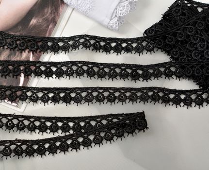 Tapes of black gentle guipure, beauty lace fabric on light background. Elastic material. Using for Atelier and needlework store.