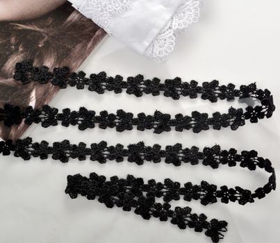 Tapes of black gentle guipure, beauty lace fabric on light background. Elastic material. Using for Atelier and needlework store.