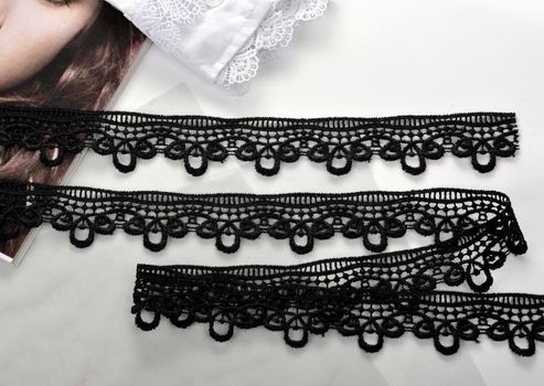 Tapes of black gentle guipure, beauty lace fabric on light background. Elastic material. Using for Atelier and needlework store.