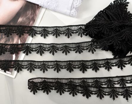 Tapes of black gentle guipure, beauty lace fabric on light background. Elastic material. Using for Atelier and needlework store.