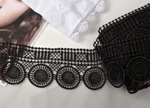 Tapes of black gentle guipure, beauty lace fabric on light background. Elastic material. Using for Atelier and needlework store.