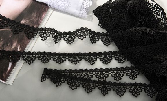Tapes of black gentle guipure, beauty lace fabric on light background. Elastic material. Using for Atelier and needlework store.