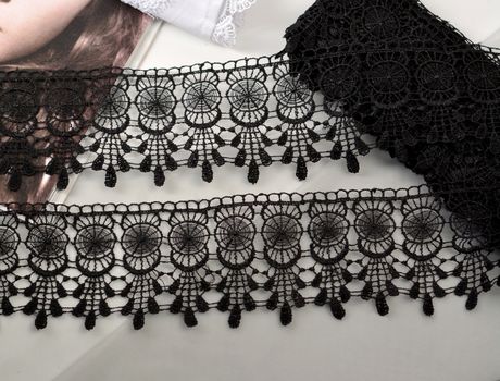 Tapes of black gentle guipure, beauty lace fabric on light background. Elastic material. Using for Atelier and needlework store.