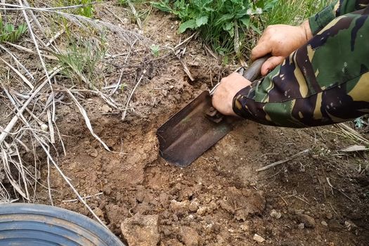 Digging with a soil shovel. A man digs a small spatula on a hole.