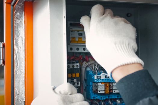 Repair work in the electric flap. The electrician handles the equipment in the electric flap with his hand in the glove.