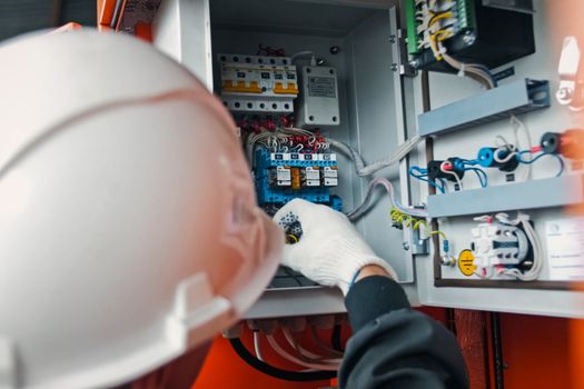 Repair work in the electric flap. The electrician handles the equipment in the electric flap with his hand in the glove.