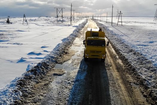 The truck rides on a winter road among the snow.