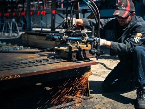 The worker cuts the sheet of metal with gas welding.