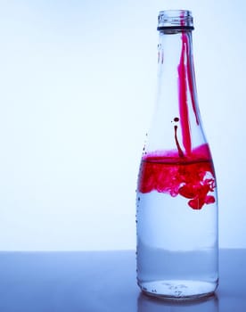 red ink mixed with water in a glass bottle on a light background. Hight quality photo