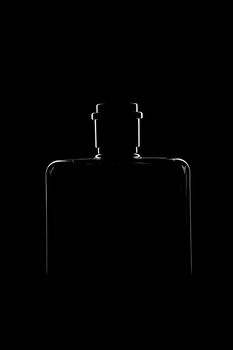 Silhouette of a bottle with a beautiful shape on a black background. High quality photo