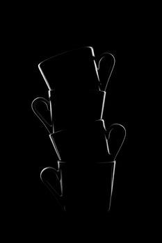 Silhouettes of small coffee cups on a black background. Beautiful shape. High quality photo