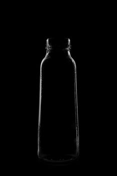 Silhouette of a bottle with a beautiful shape on a black background. High quality photo