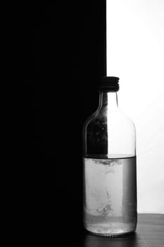 A small bottle on a black and white background. Half black and half white. High quality photo