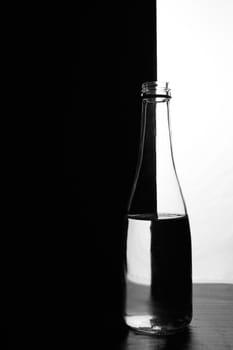 A bottle of water on a black and white background. Optical over-reflection effect. High quality photo