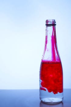 red ink mixed with water in a glass bottle on a light background. Hight quality photo