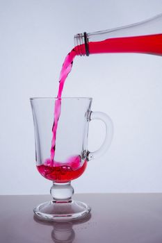 red liquid poured into a glass glass on a white background with bubbles. Hight quality photo