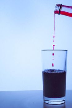 pour red wine into a glass cup with blue liquid. Hight quality photo