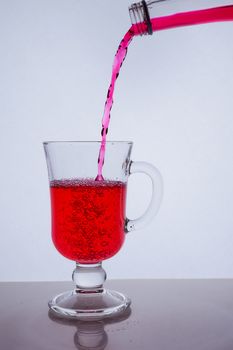 red liquid poured into a glass glass on a white background with bubbles. Hight quality photo