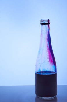 a blue liquid is poured into a glass bottle. Light blue background. Hight quality photo