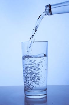 fresh clean water is poured from a bottle into a glass cup. Light background.. Hight quality photo
