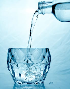 fresh clean water is poured from a bottle into a glass cup. Light background.. Hight quality photo