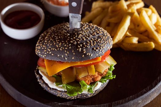 Black burger with sesame seeds with fries and salad of cabbage closeup photo