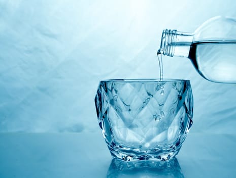 fresh clean water is poured from a bottle into a glass cup. Light background.. Hight quality photo