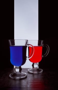 silhouettes of two glasses on a black and white background. Blue and red liquid. Hight quality photo