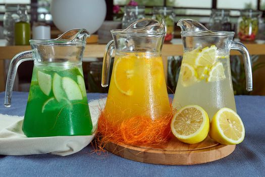 three varieties of summer lemonade in jugs on a blue tablecloth closeup photo