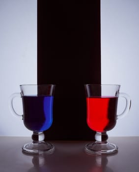 silhouettes of two glasses on a black and white background. Blue and red liquid. Hight quality photo