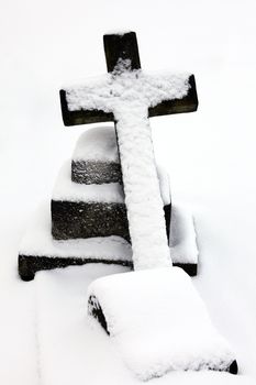 Old snow covered granite tombstone stone cross found in an old graveyard in a Christmas winter season stock photo