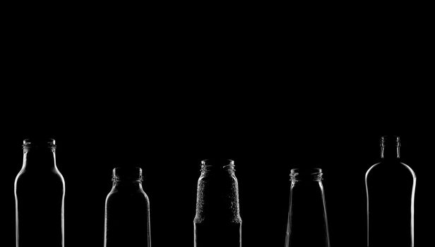 The silhouettes of bottles with various beautiful shapes on a black background. Banner for advertising with a place to insert text. High quality photo