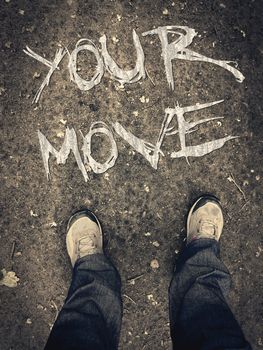 Motivation poster with lettering words "your move". Legs in shoes top view. Conceptual written message for moving forward. First person view of boots on the ground. Grunge motivational writing.